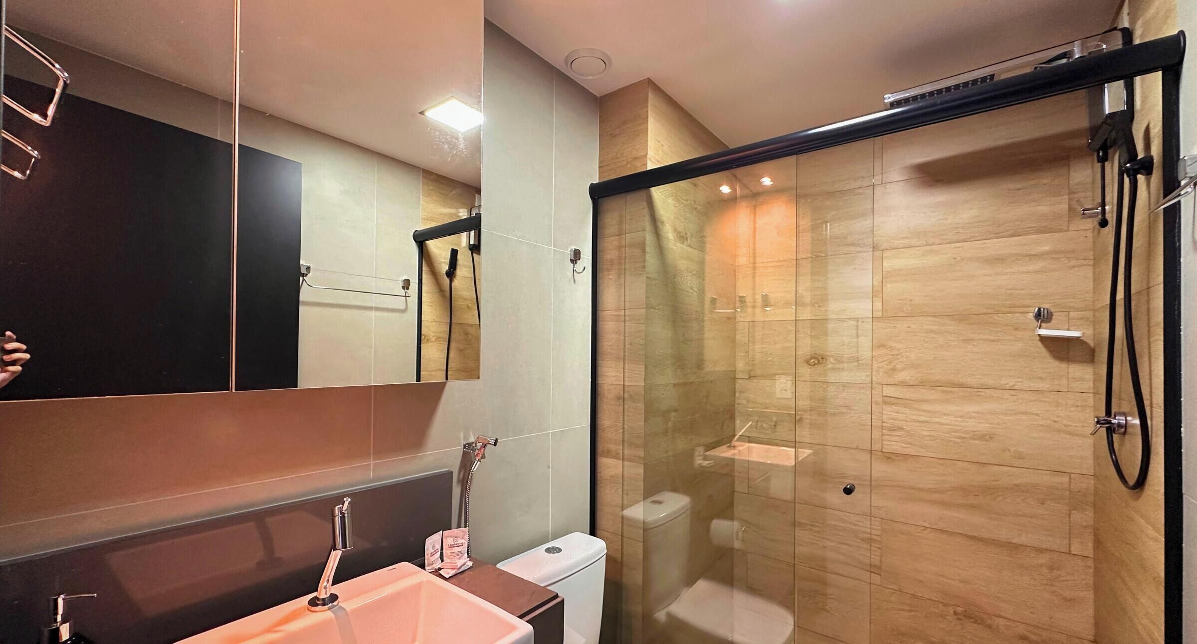 Une salle de bain moderne avec une douche à parois de verre, un lavabo avec un miroir et des toilettes.