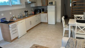 A compact kitchen with white cabinets, a microwave, a coffee maker, and a dining area with white chairs and a table.
