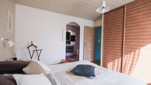 Un dormitorio con cama, almohadas, una lámpara colgante y una puerta de madera.