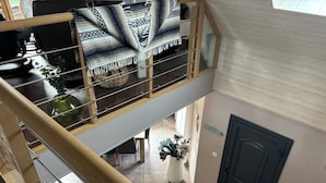 Un interior de varios niveles con una escalera, una puerta y una planta.