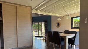 Un comedor moderno con una mesa y sillas de madera, un ventanal con vistas a la vegetación y un techo con vigas a la vista.