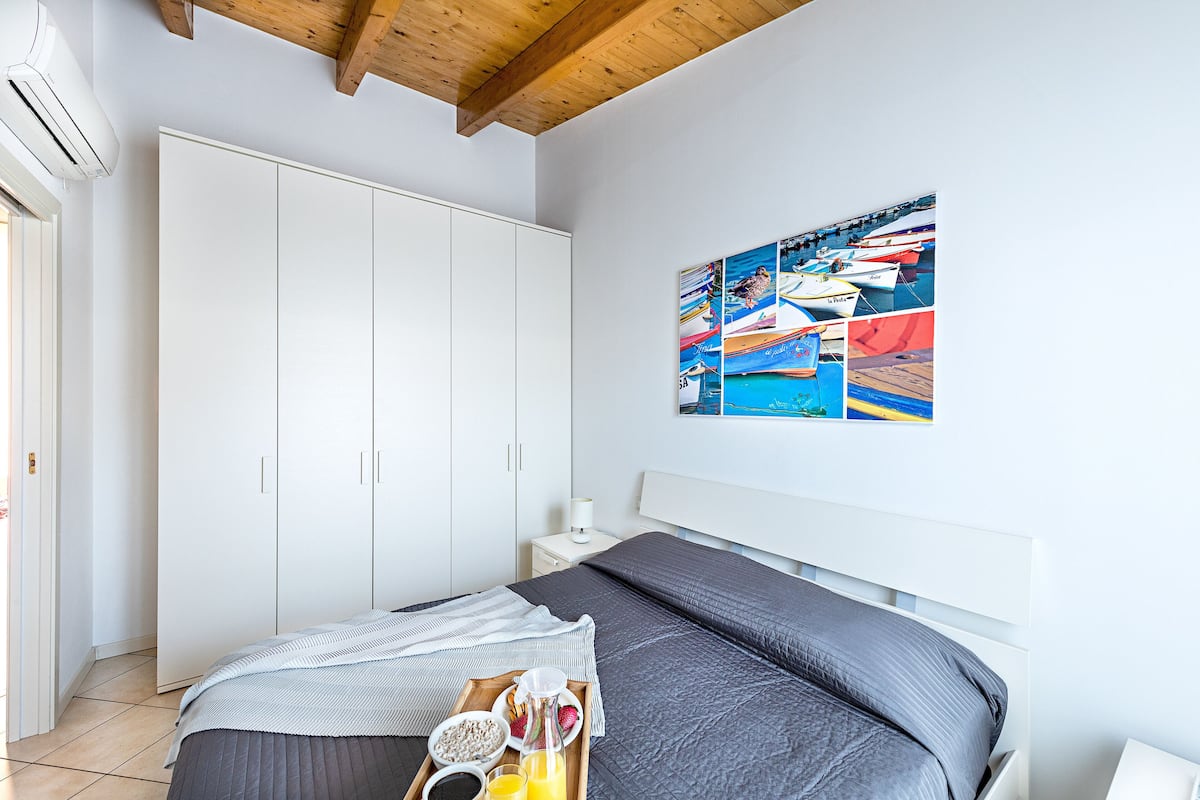 Une chambre avec un grand lit, une armoire, une table de chevet et un mur décoré d’un collage de photos de bateaux.