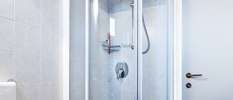 A modern bathroom with a glass-enclosed shower, a sink, and blue-tiled flooring.