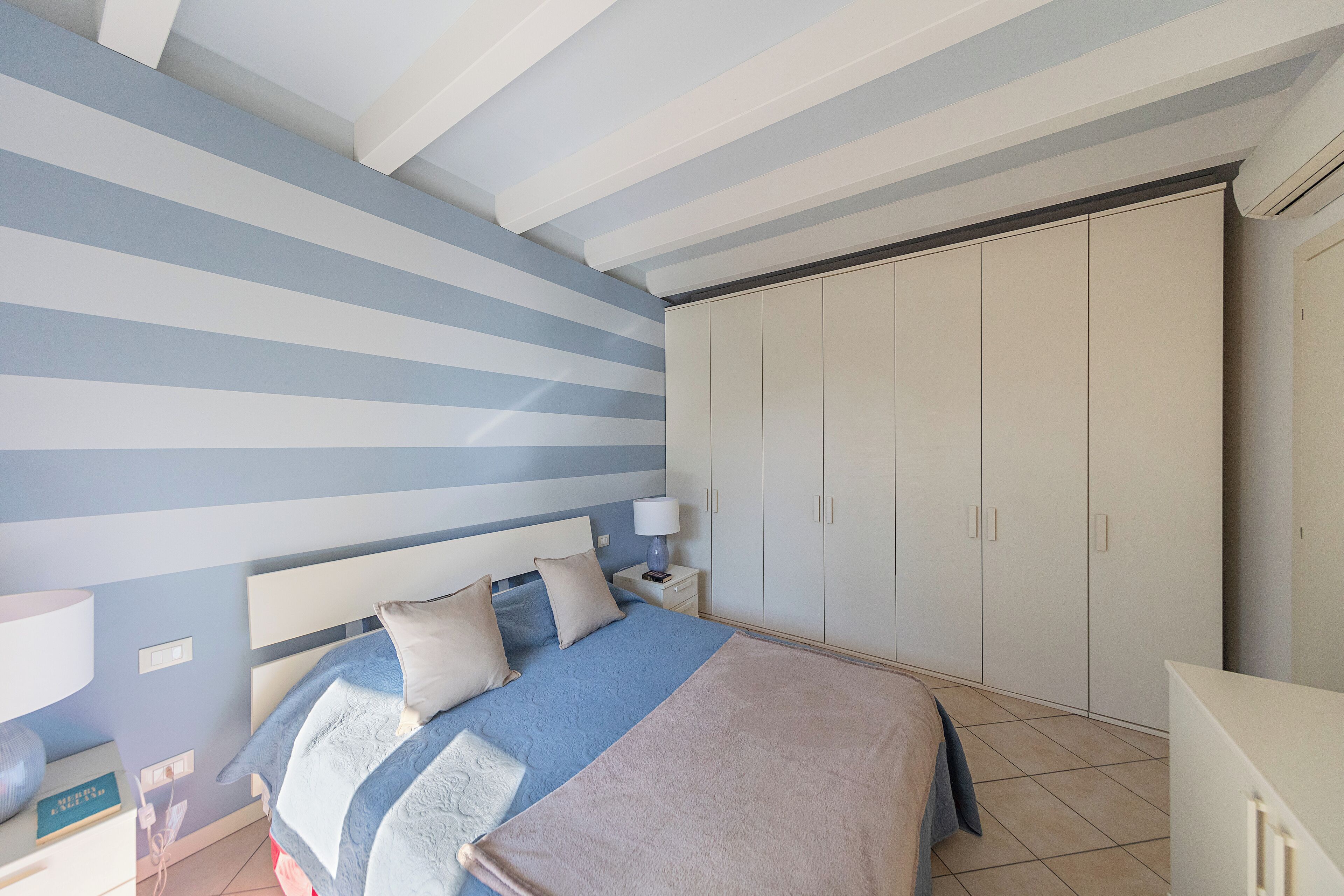 A bedroom with a bed, nightstand, and wardrobe.