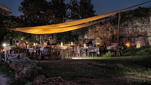An outdoor dining area with tables and chairs, a canopy, and a stone wall in the background. - Cozy villa with pool nestled among the ancient olive trees of Cilento  (Capaccio Paestum)