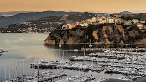 A coastal town with a marina filled with boats, surrounded by hills and buildings. - Cozy villa with pool nestled among the ancient olive trees of Cilento  (Capaccio Paestum)