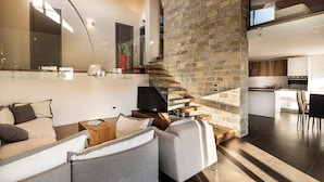 A modern living room with a stone staircase, a sofa, a coffee table, and a TV. - Cozy villa with pool nestled among the ancient olive trees of Cilento  (Capaccio Paestum)