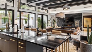 Una cocina moderna con una isla grande, una zona de comedor con asientos de cuero y una chimenea.