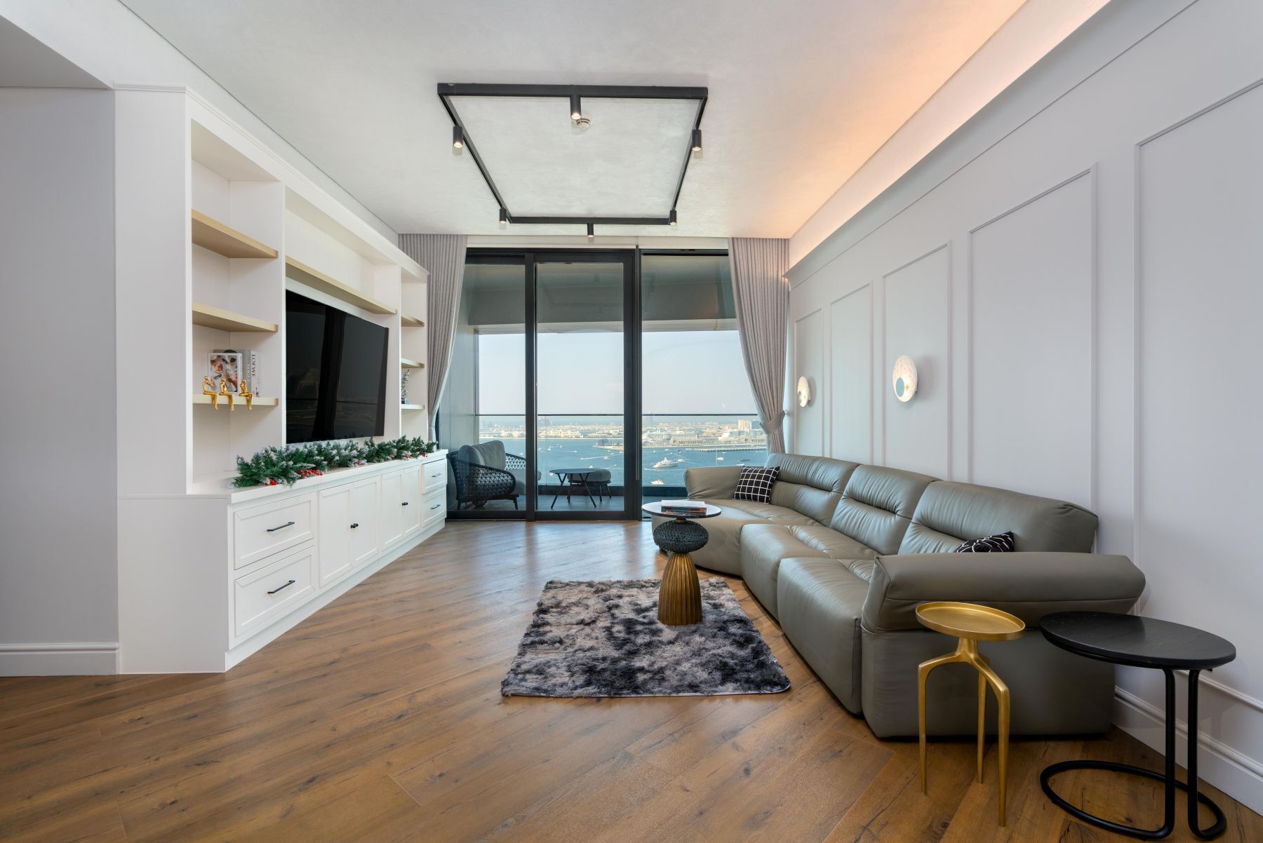 Un salon moderne doté d’un grand canapé, d’un téléviseur à écran plat, d’un coin repas avec une table et des chaises, et offrant une vue sur la ville grâce à de grandes fenêtres.