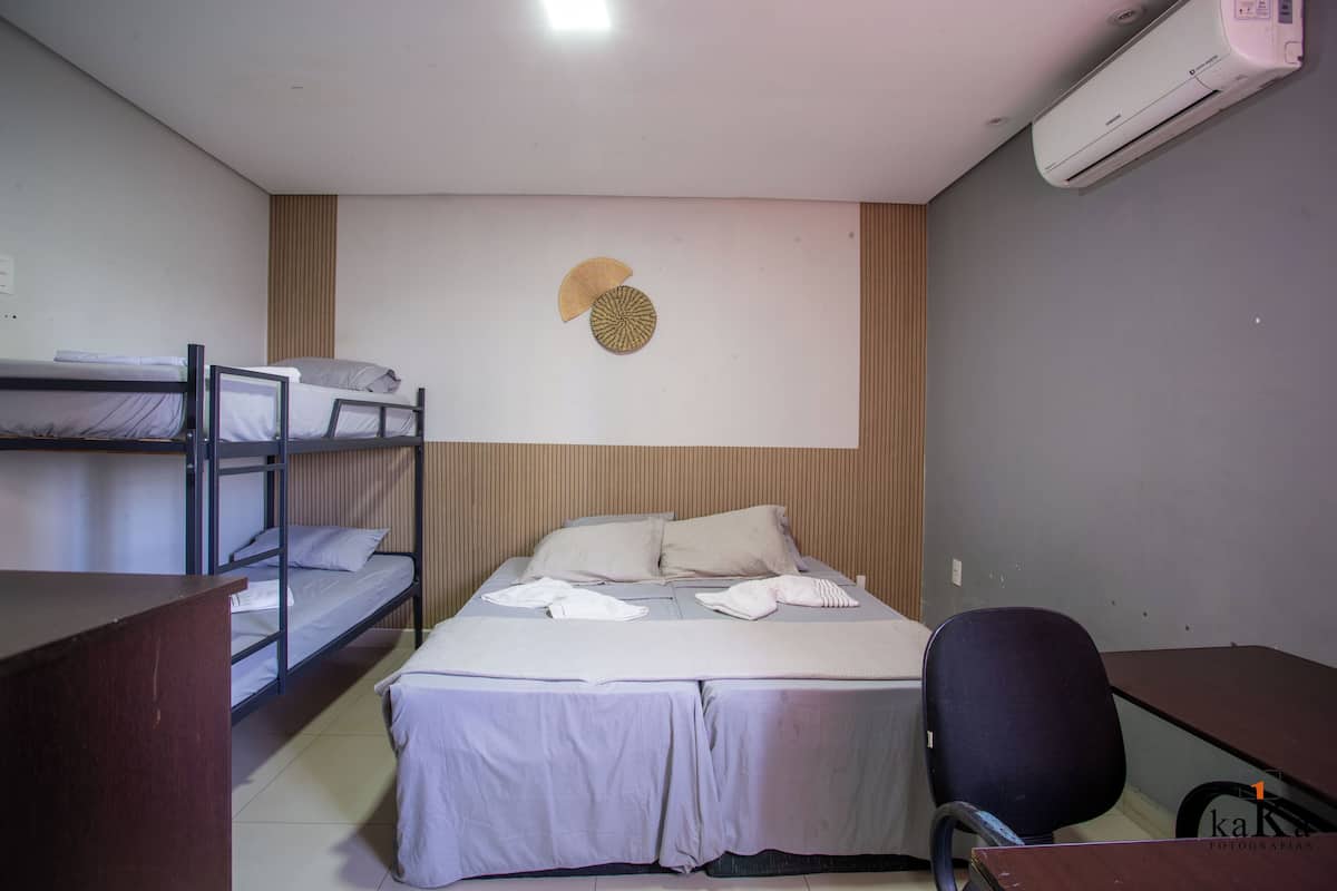 A dormitory room with bunk beds, a desk, and a chair.