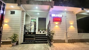 Entrada de un hotel con un cartel que dice "SILVER INN" y un acceso con puerta metálica y escalones que conducen a la entrada.