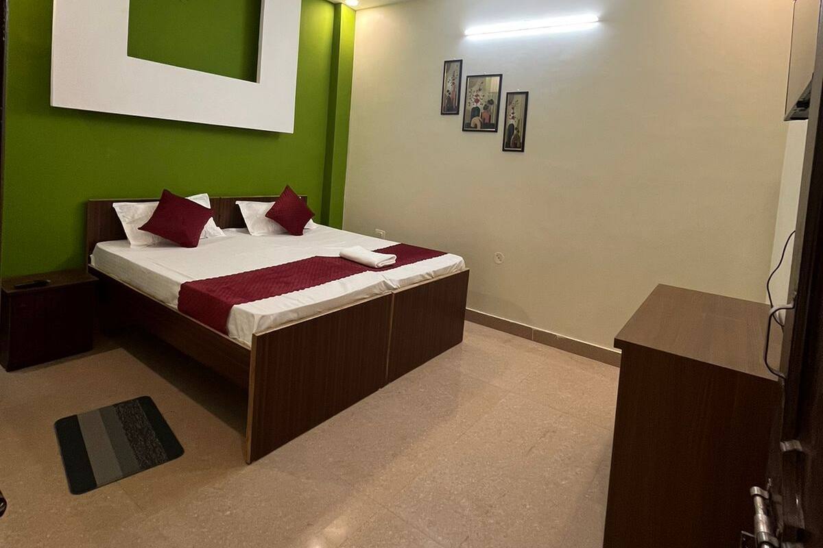 A bedroom with a bed, a desk, a ceiling fan, and artwork on the wall.