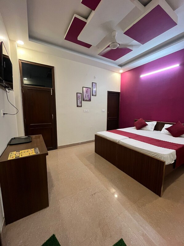 A bedroom with a bed, a desk, and a ceiling fan.