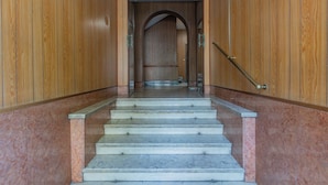 A staircase with marble steps leading to a wooden door with a metal handrail.