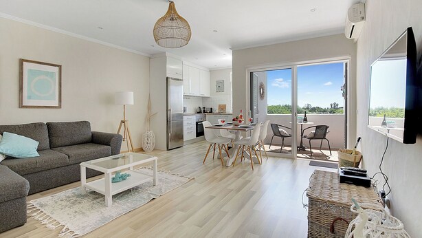 A modern living room with a sofa, coffee table, and dining area. - Fabulous apartment in beautiful Quinta do Paraiso (Carvoeiro)