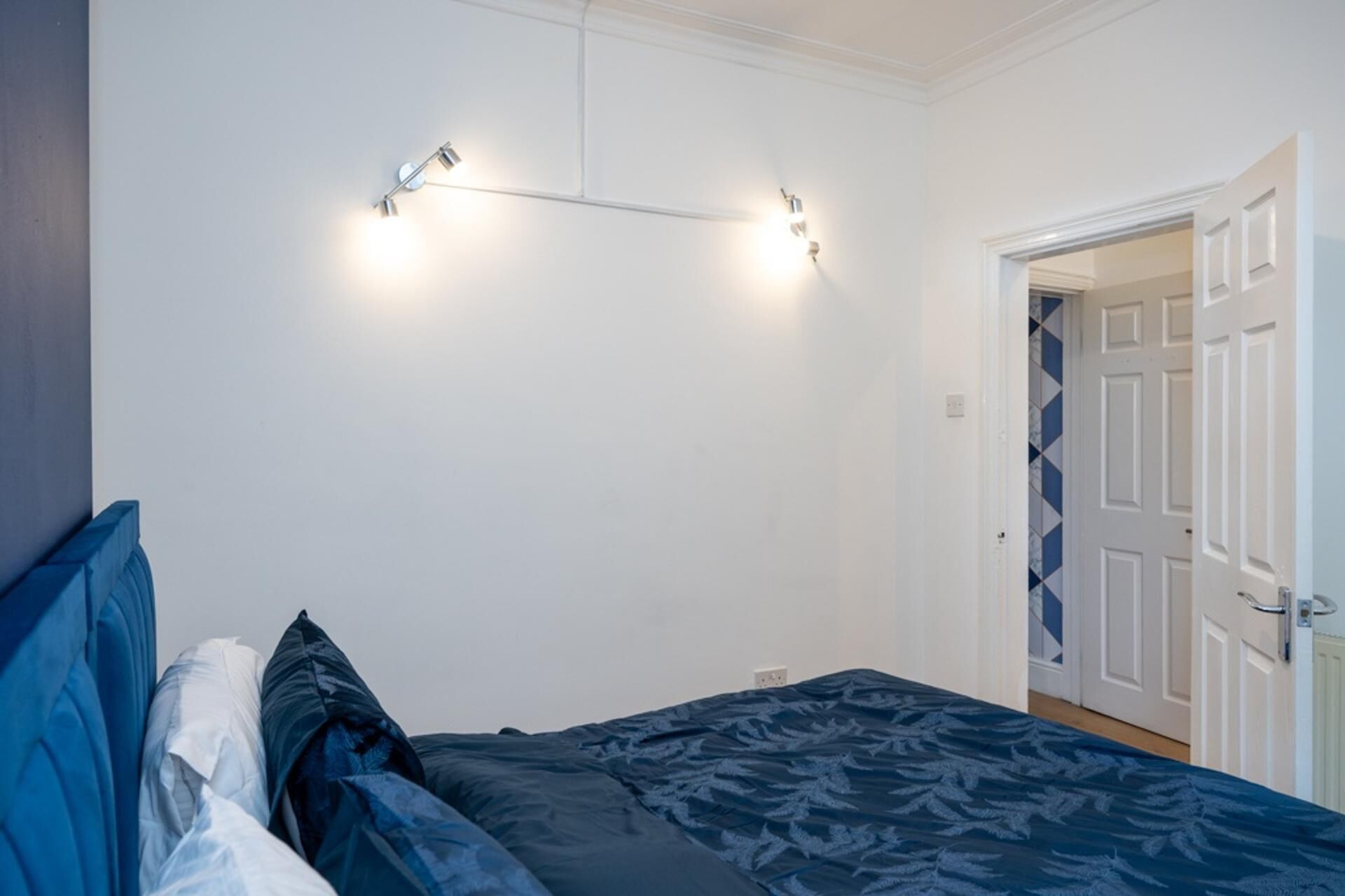 A bedroom with a bed, a wall-mounted light fixture, and a door.