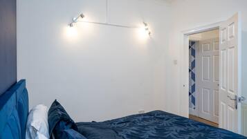 A bedroom with a bed, a wall-mounted light fixture, and a door.