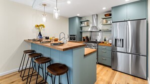 Une cuisine moderne dotée d’un îlot central, de tabourets de bar, d’appareils électroménagers en acier inoxydable et de meubles de couleur bleu clair.