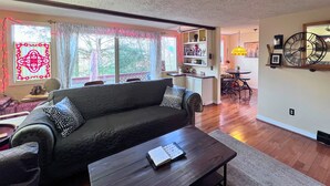 A cozy living room with a dark-colored sofa, a wooden coffee table, and a dining area with a small table and chairs. - Charming 1 bedroom condo-walking distance to slopes (Sugar Mountain)