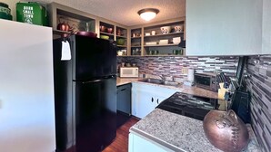 A compact kitchen with a black refrigerator, white cabinets, a microwave, and a sink. - Charming 1 bedroom condo-walking distance to slopes (Sugar Mountain)