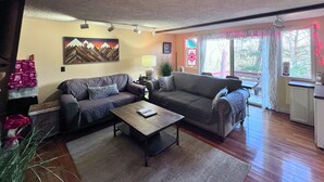 A living room with two sofas, a coffee table, and a window with curtains. - Charming 1 bedroom condo-walking distance to slopes (Sugar Mountain)