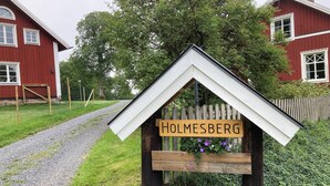 Et træskilt med navnet "HOLMESBERG" på et hus.
