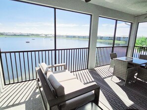 Un espace extérieur abrité avec vue sur un lac, un coin salon avec une table et une rambarde.