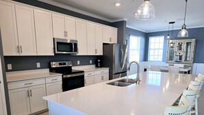 Una cocina moderna con armarios blancos, electrodomésticos de acero inoxidable y una isla grande con asientos.