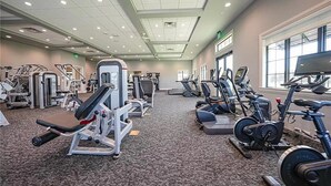 Un gimnasio con varios equipos de ejercicio, como cintas de correr, bicicletas estáticas y máquinas de pesas.