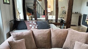 A cozy living room with a large L-shaped sofa, a patterned throw, and a dining area in the background. - La Ferme des Pins, relaxation with family and friends, 15 minutes from the beach (Carly)