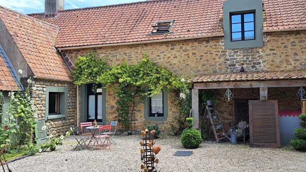 A stone building with a tiled roof, a small garden area with a table and chairs, and a ladder leaning against the wall. - La Ferme des Pins, relaxation with family and friends, 15 minutes from the beach (Carly)
