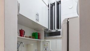 Cocina compacta con gabinetes blancos, encimera de granito, horno empotrado y un ventanal sobre el lavamanos.