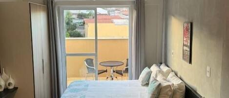 Habitación de hotel con cama, una mesita y vistas al exterior.
