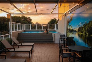 An outdoor swimming pool area with steps leading down to the water, surrounded by lounge chairs and a table. - Esuites Sorocaba (Sorocaba)