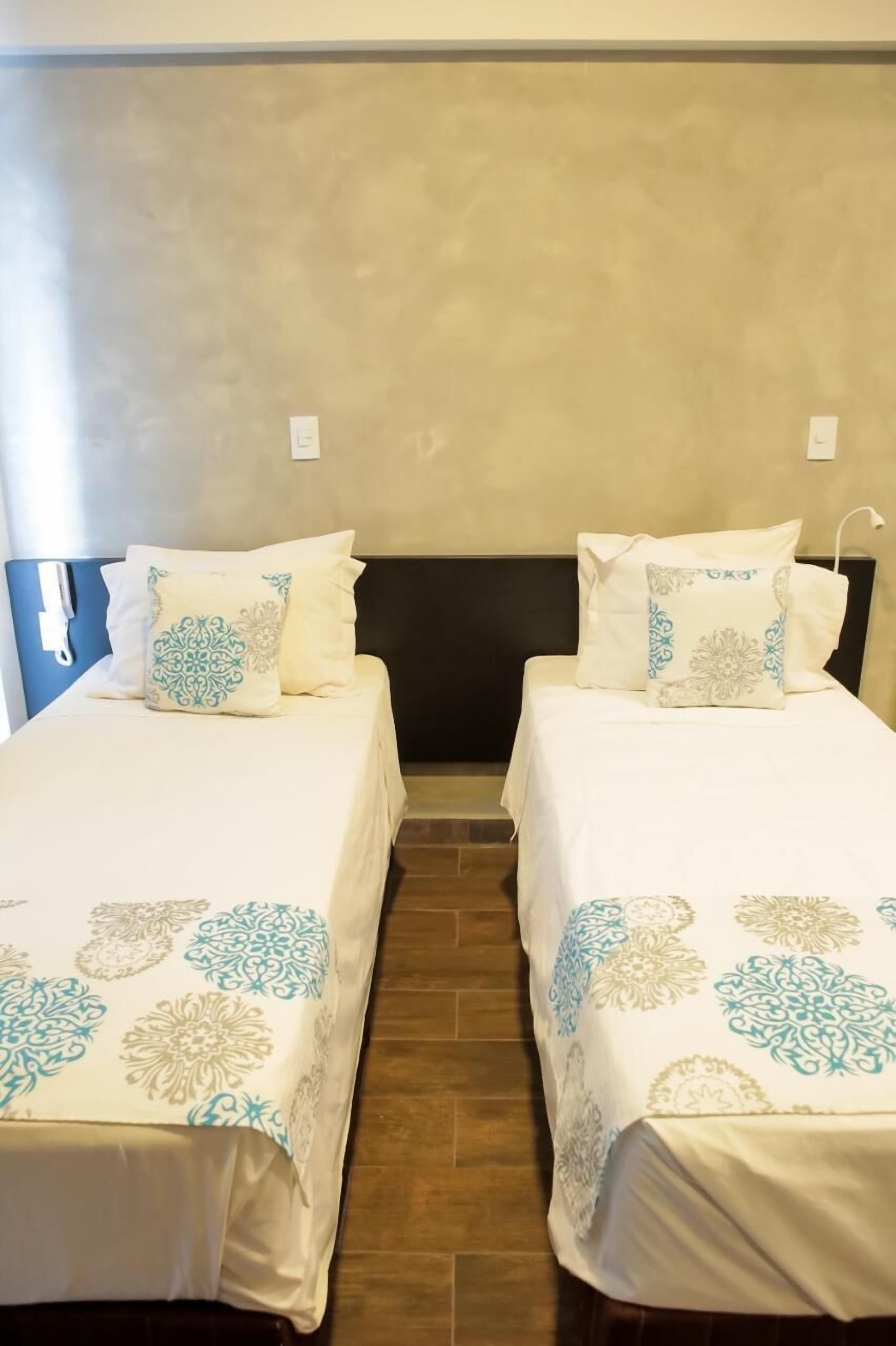Una habitación de hotel con dos camas individuales, cada una con una colcha estampada y almohadas a juego.