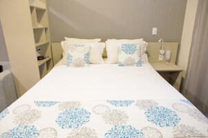 Una habitación de hotel con cama, dos mesitas de noche y una lámpara de pared.