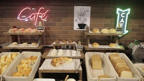 Een café met diverse gebakjes op houten tafels, zoals donuts, gebak en brood.