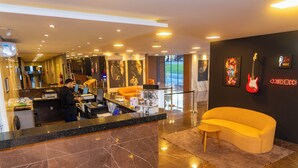 Een moderne lobby met een receptiebalie, een gele bank en een rode elektrische gitaar.