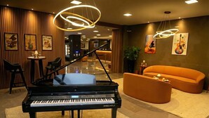 Een vleugelpiano in een goed verlichte lobby met een moderne bank en een receptiebalie.