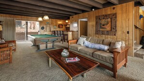 A cozy living room with a pool table, wooden furniture, and a large painting on the wall.