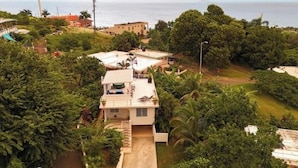 A residential property with a two-story structure, a covered patio, and a view of the sea.