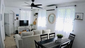 A living room with a sofa, TV, and dining table.
