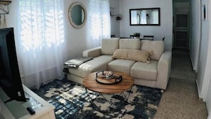 A living room with a sofa, a coffee table, a TV, and a ceiling fan.