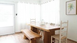 Une table de salle à manger en bois, avec un banc, deux chaises et un bocal en verre posé sur la table.