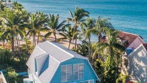 Une maison bleue avec un balcon, entourée de palmiers et offrant une vue sur l’oc éan.