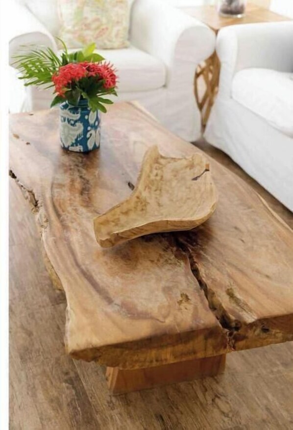 Ett rustikt träbord, perfekt som soffbord, med en unik och naturlig design, tillsammans med en vas med röda blommor.