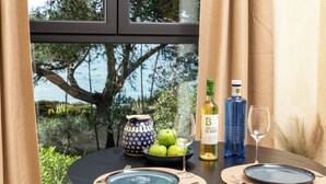 A dining table with plates, cutlery, a bowl of green apples, a wine glass, a bottle of wine, and a decorative vase. - Ocean View Apartment with rooftop terrace (Carvoeiro)