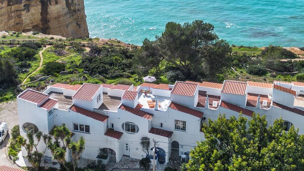 A coastal building with multiple balconies, a paved courtyard, and a view of the ocean. - Ocean View Apartment with rooftop terrace (Carvoeiro)