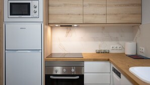 A modern kitchen with a built-in microwave, oven, and dishwasher, wooden cabinets, marble backsplash, and a wooden countertop.