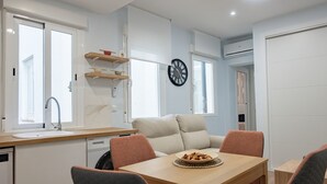 A compact kitchen with a sink, countertop, and a dining area with a table and chairs.